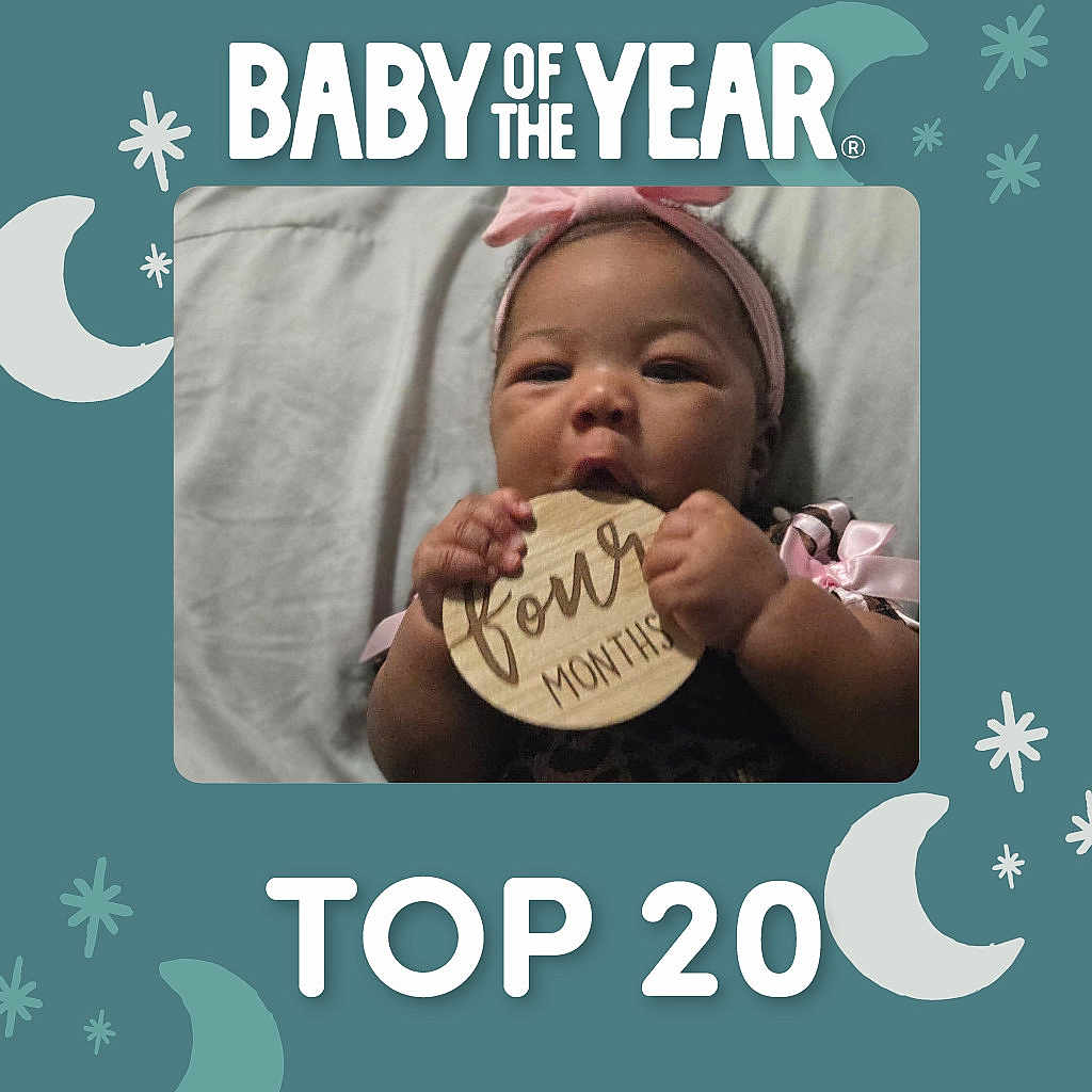 Samiyah is registered to the contest to win money with this photo: baby, infant, child, portrait, smiling, headband, pink, milestone, four_months, wooden_sign, chewing, hands, lying_down, blanket, bed, indoor, moon, stars, baby_of_the_year, top_20