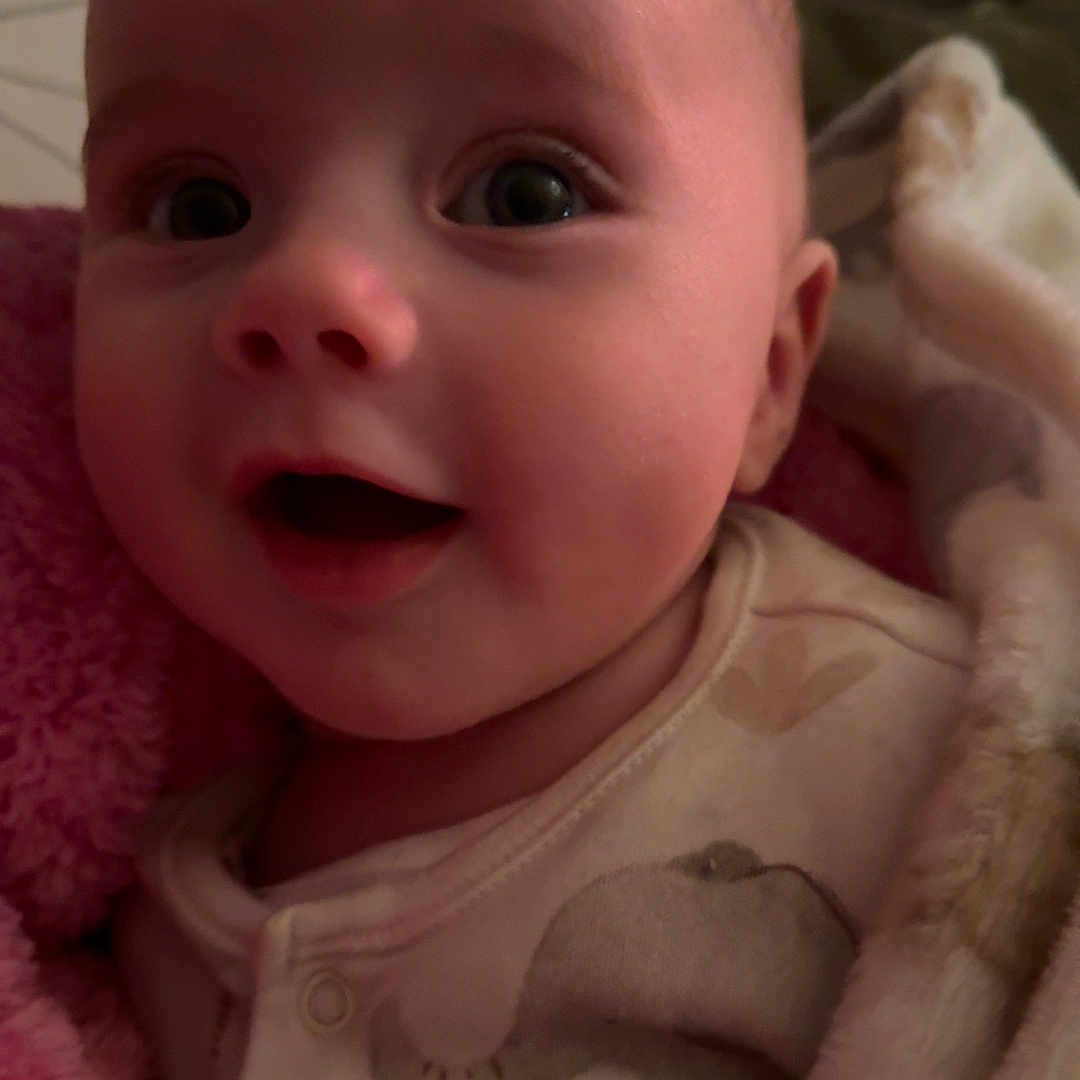 Covey is registered to the contest to win money with this photo: baby, blanket, child, closeup, clothing, cozy, cute, expression, eyes, face, happy, indoors, infant, newborn, onesie, person, portrait, skin, smiling, soft