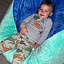 Ezra joined the competition — help win amazing prizes! toddler, child, smiling, bean_bag, pajamas, dinosaur_print, indoor, floor, plush, blue, green, clothing, person, portrait, happy, casual, relaxed, home, cute, young