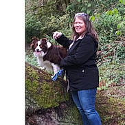 Ozzy joined the competition — help win amazing prizes! woman, dog, leash, forest, tree, moss, log, outdoor, nature, greenery, smile, casual_clothing, jeans, jacket, pet, animal, happy, standing, canine, walking