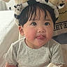 Kaylene is registered to the contest to win money with this photo: baby, child, tongue_out, headband, cow_pattern, horns, bandaged_hand, gray_shirt, indoor, cute, playful, face, person, young_child, portrait, sitting, soft_lighting, black_hair, skin, expression