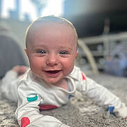 Harry joined the competition — help win amazing prizes! baby, smiling, infant, lying_down, carpet, white_clothing, colorful_spots, happy, indoor, closeup, face, child, cute, soft_light, home, portrait, young, person, skin, eyes