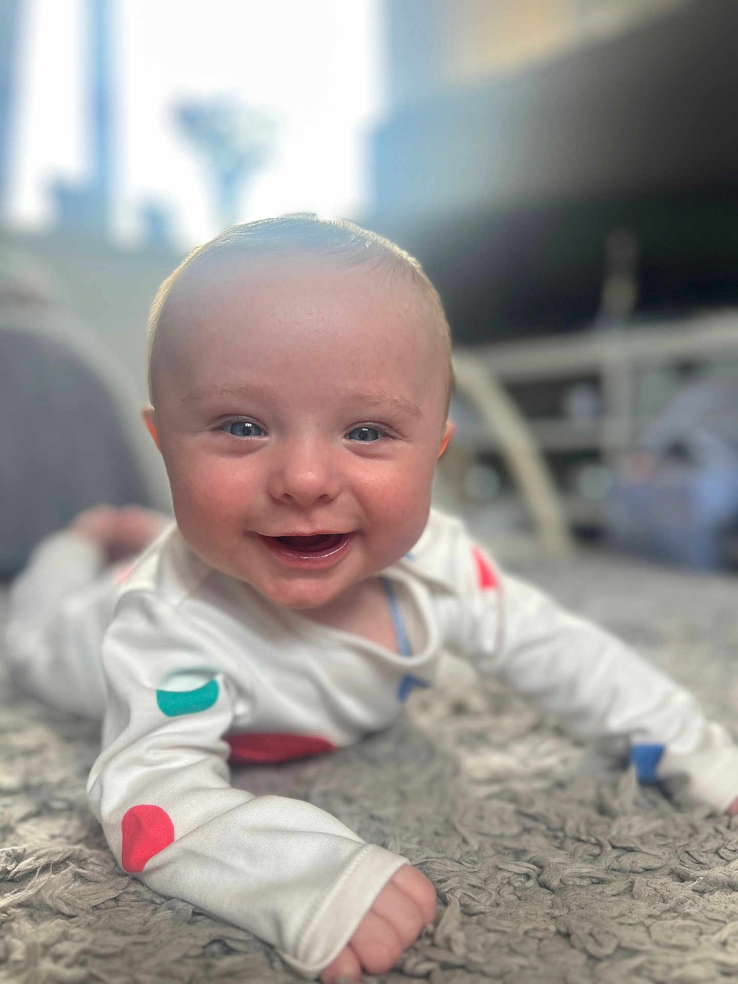 Harry joined the competition — help win amazing prizes! baby, smiling, infant, lying_down, carpet, white_clothing, colorful_spots, happy, indoor, closeup, face, child, cute, soft_light, home, portrait, young, person, skin, eyes