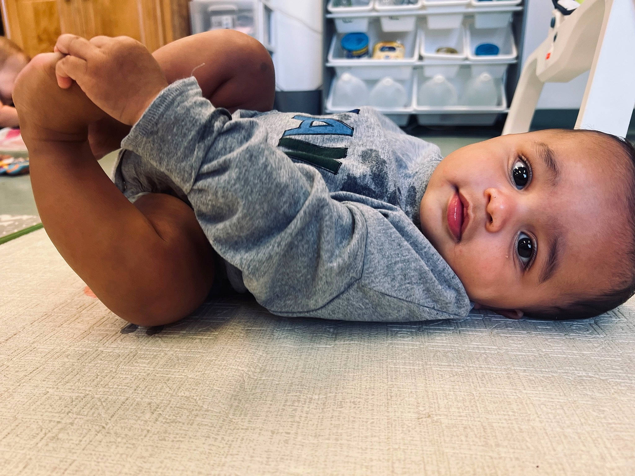 Kamden is registered to the contest to win money with this photo: arm, baby_toddler_clothing, barefoot, comfort, elbow, finger, floor, flooring, foot, gesture, hand, human_body, human_leg, joint, knee, person, shoulder, sitting, thigh, thumb