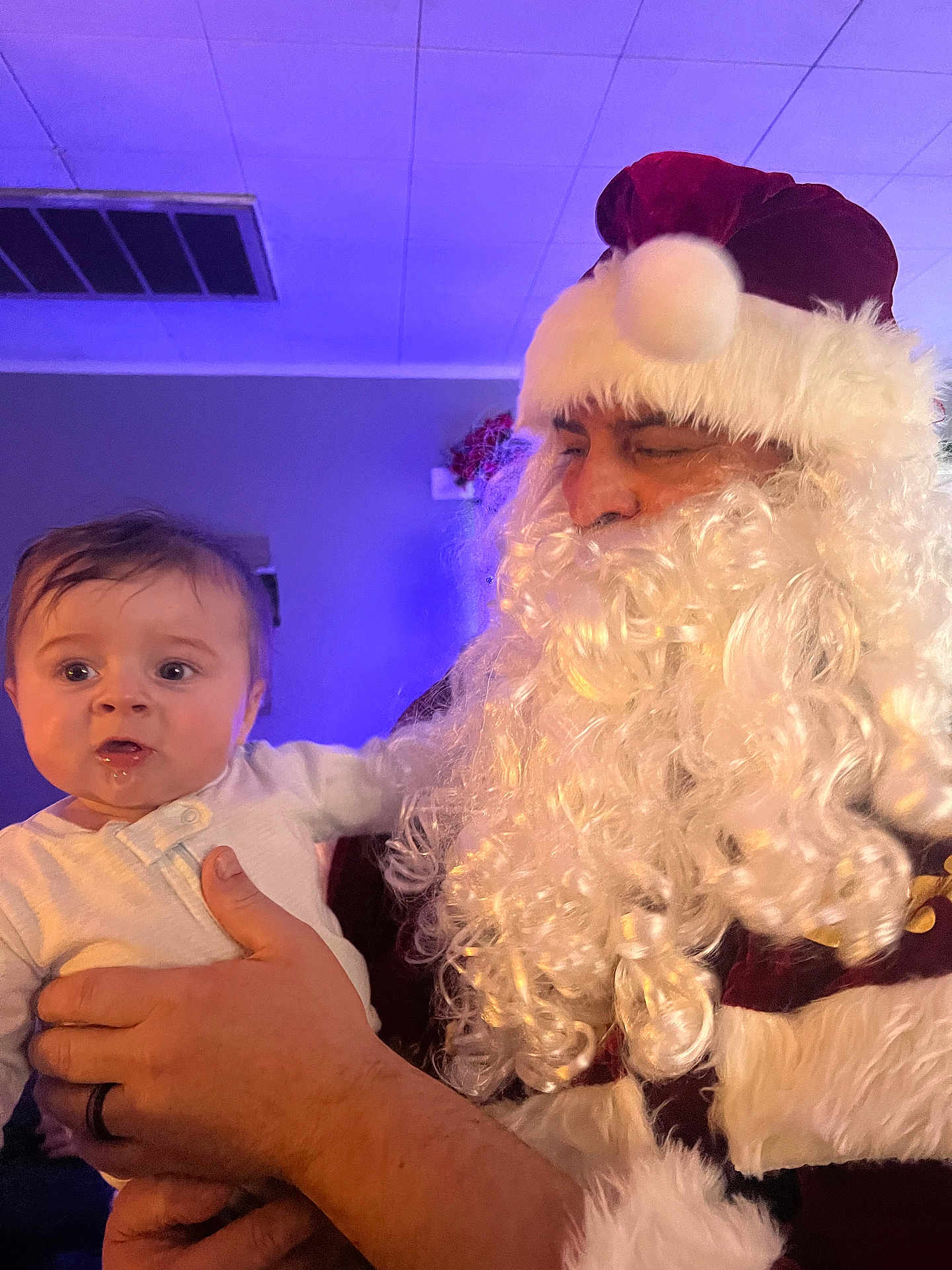 Hayden joined the competition — help win amazing prizes! baby, child, person, santa_claus, costume, beard, hat, indoor, lighting, hand, holding, portrait, curious, drool, white_clothing, red_hat, adult, celebration, holiday, face
