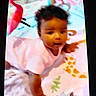 animal_prints, baby, baby_girl, blanket, child, colorful, crawling, curly_hair, cute, floor, giraffe, indoor, infant, person, pink_clothing, play_mat, playtime, raccoon, soft_toys, young_child