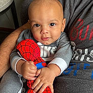 Apollo is registered to the contest to win money with this photo: baby, child, plush_toy, spiderman, grey_clothing, person, arms, indoor, portrait, close_up, holding, cute, smiling, young_child, soft_toy, casual_wear, furniture, hand, face, comfort
