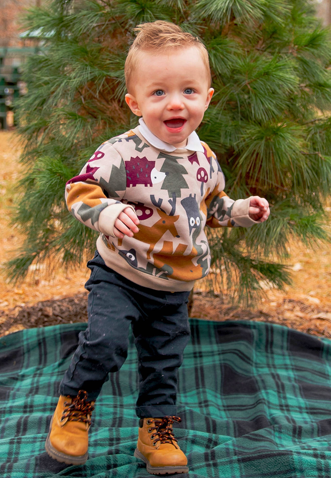 Azaiah is registered to the contest to win money with this photo: baby, child, clothing, event, facial_expression, fun, grass, green, happy, joy, leaf, pattern, people_in_nature, person, plaid, plant, sitting, smile, tartan, toddler