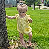 toddler, child, yellow_outfit, tree, grass, outdoor, sunny, walking, baby, person, nature, greenery, residential_area, summer, cute, small_hair_tie, barefoot, young_child, playing, daylight