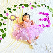 Kawsar joined the competition — help win amazing prizes! baby, child, dress, purple, flower, leaves, white_sheet, socks, headband, portrait, milestone, celebration, cute, infant, laying_down, floral_arrangement, number_three, soft_lighting, indoor, adorable
