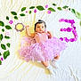 baby, child, dress, purple, flower, leaves, white_sheet, socks, headband, portrait, milestone, celebration, cute, infant, laying_down, floral_arrangement, number_three, soft_lighting, indoor, adorable