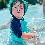 Yacine a rejoint le concours — aidez-le/la à gagner de superbes lots ! blue, child, cute, daytime, face, happy, hat, nature, outdoor, person, playing, pool, sitting, skin, summer, sunny, swimwear, toddler, water, water_droplets