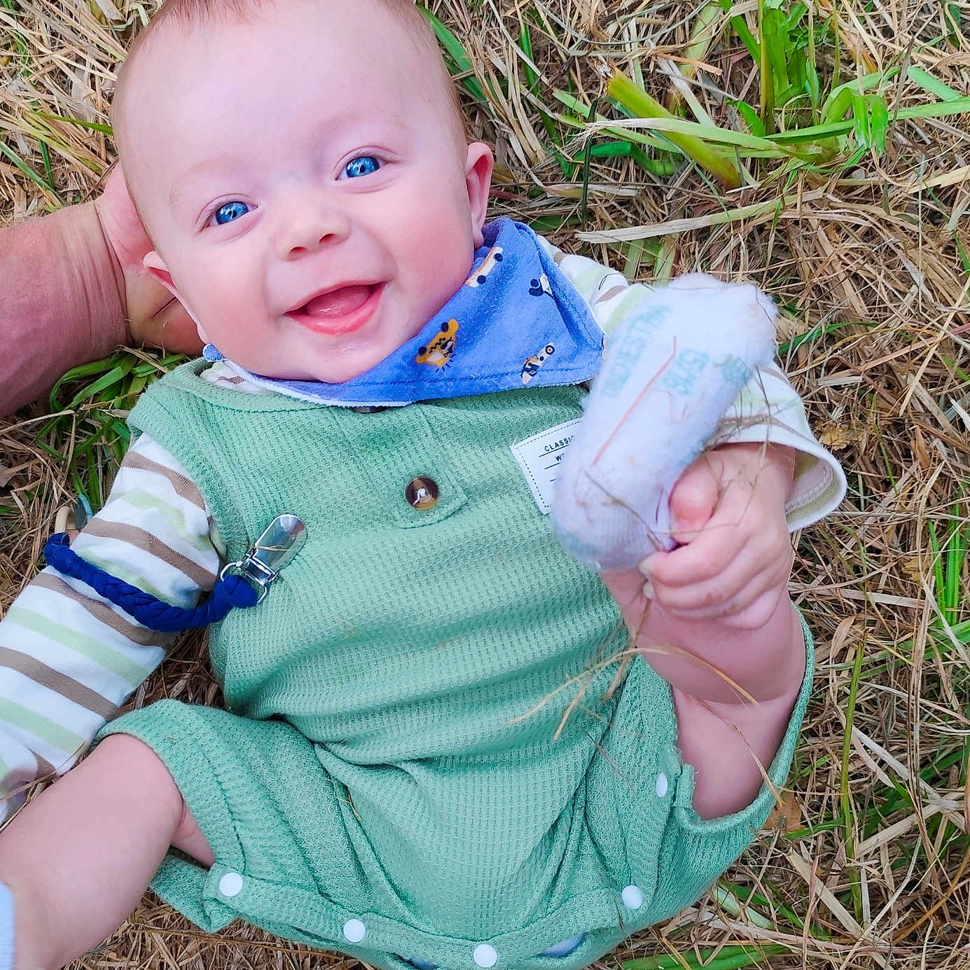 Oban participe au concours pour gagner de l'argent avec cette photo : baby, bib, blue_eyes, child, cute, grass, green_clothing, hand, happy, head_support, infant, lying_down, nature, outdoor, person, playful, portrait, smiling, sock, straw