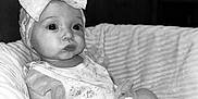 Lynnix is registered to the contest to win money with this photo: baby, infant, child, bow, headband, dress, frilly, cushion, chair, black_and_white, portrait, cute, indoors, sitting, small_hands, socks, closeup, expression, soft_light, cozy