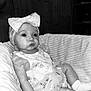 baby, infant, child, bow, headband, dress, frilly, cushion, chair, black_and_white, portrait, cute, indoors, sitting, small_hands, socks, closeup, expression, soft_light, cozy