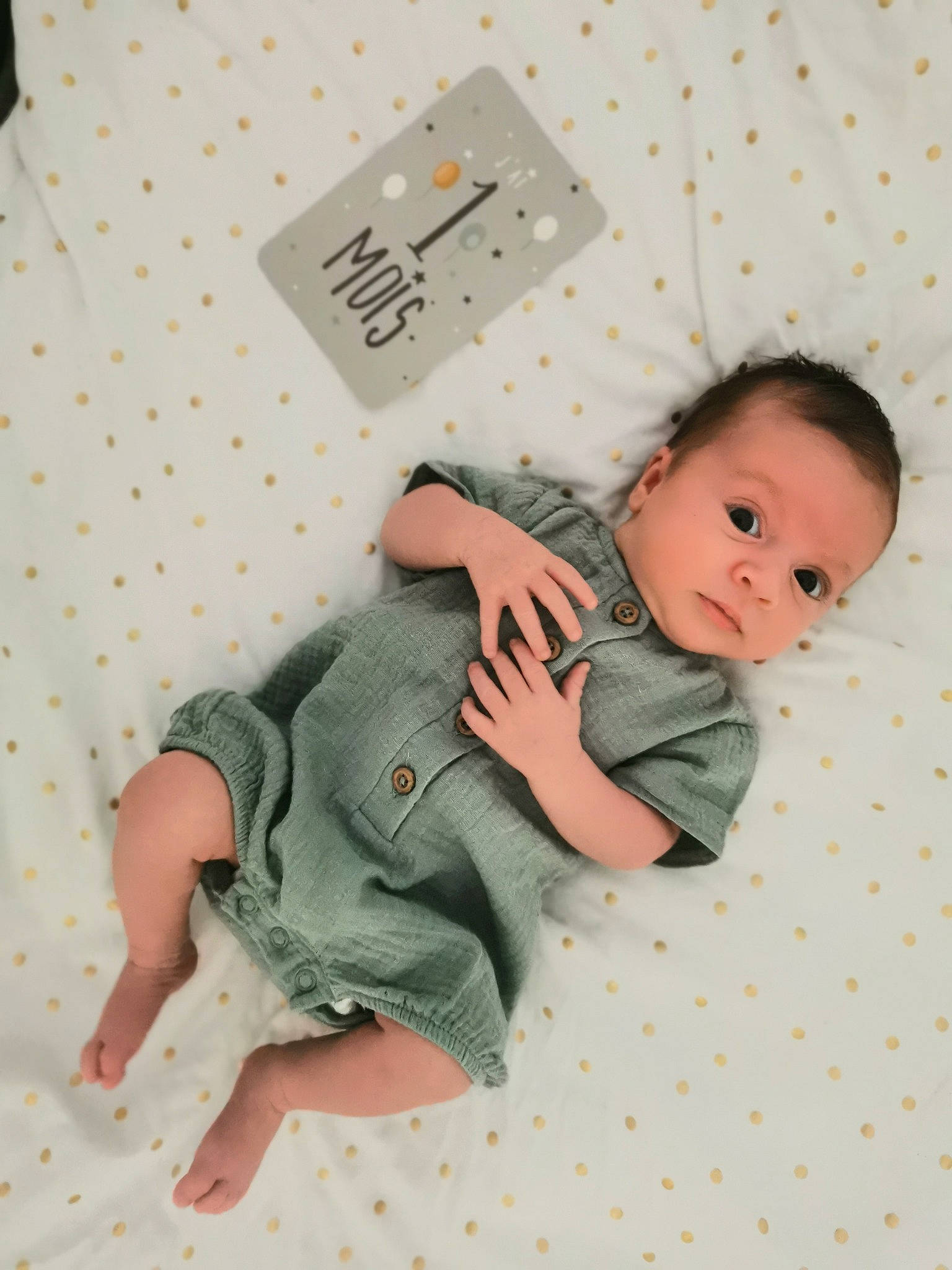 Loan participe au concours pour gagner de l'argent avec cette photo : baby, baby_products, baby_toddler_clothing, barefoot, bedding, child, comfort, foot, linens, pattern, person, product, room, sitting, sleeve, sock, t_shirt, textile, thigh, thumb