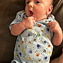 baby, infant, onesie, clothing, cartoon, crab, blue, brown_leather, fist, curious, wide_eyes, skin, cute, laying_down, expression, young_child, person, indoors, child, newborn