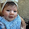 baby, child, infant, portrait, face, smiling, eyes, bow, headband, blue_clothing, bib, sitting, held, adult_hand, outdoor, stone_background, stroller, close_up, happy, photography
