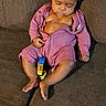 baby, child, sleeping, couch, furniture, indoors, onesie, toy, relaxing, infant, peaceful, cozy, purple_clothing, hair, legs, feet, hand, face, resting, living_room