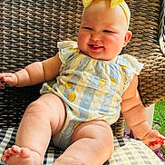 Cali joined the competition — help win amazing prizes! baby, child, smiling, yellow_bow, romper, striped_clothing, lemon_print, wicker_chair, checkered_cushion, outdoor, greenery, sunlight, cute, happy, infant, seated, plump_legs, headband, portrait, summer