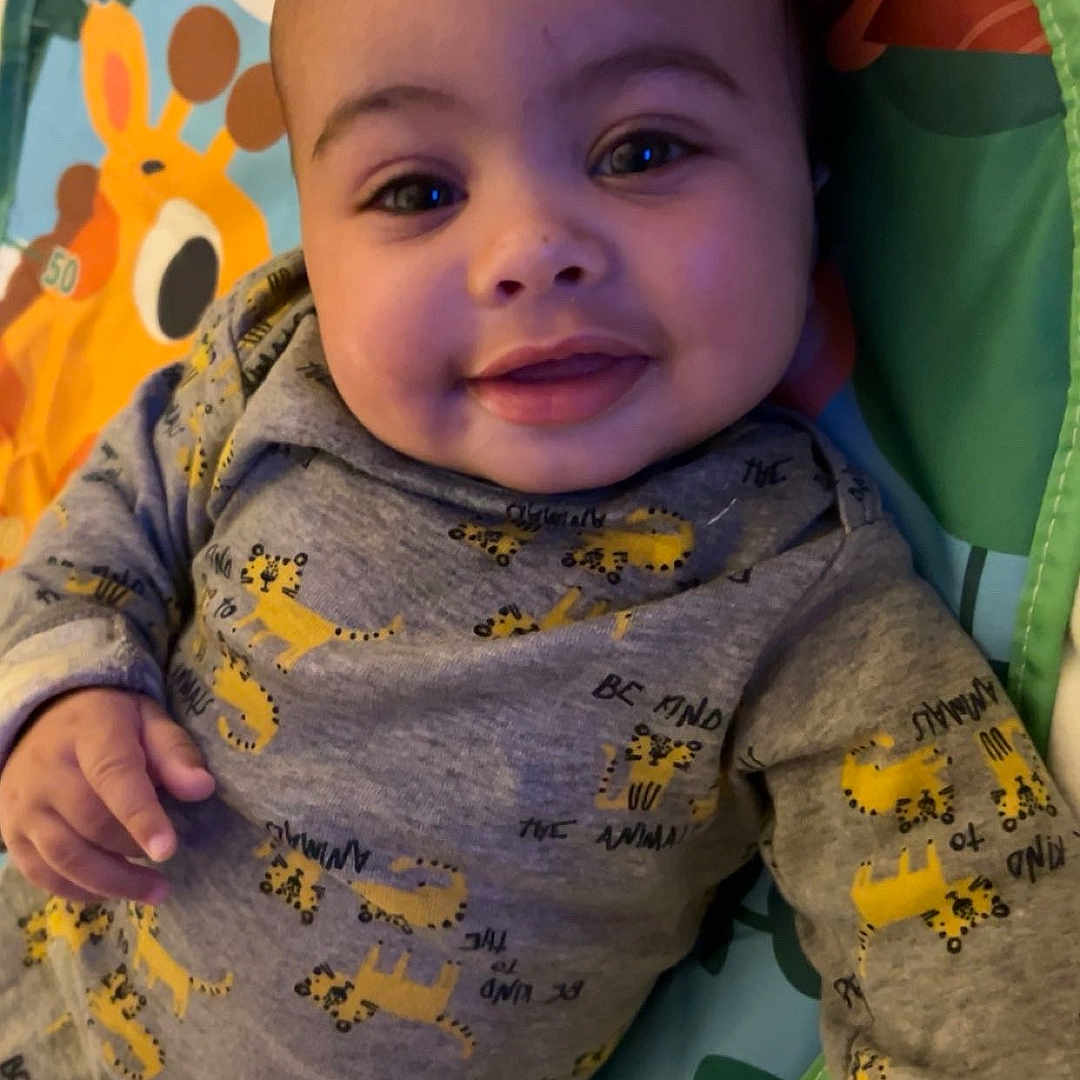 Zylo joined the competition — help win amazing prizes! baby, child, clothing, colorful, cute, face, giraffe, grey_outfit, hand, happy, indoors, infant, lying_down, person, play_mat, portrait, smiling, soft_lighting, yellow_cheetah_prints, young