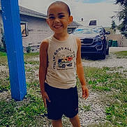 Daelyne is registered to the contest to win money with this photo: child, smiling, outdoor, grass, gravel, car, blue_post, shorts, sleeveless_shirt, sandals, happy, person, nature, daytime, cloudy_sky, house, tree, portrait, casual_clothing, young