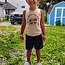 child, smiling, outdoor, grass, tank_top, shorts, sandals, car, shed, tree, sky, clouds, ankle_band, greenery, house, daytime, backyard, person, happy, portrait