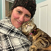 Tango joined the competition — help win amazing prizes! woman, cat, smiling, knitted_hat, coat, tabby_cat, indoor, affection, closeup, face, pet, happy, warm_clothing, embrace, collar, blue_eyes, feline, companion, portrait, human