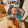 toddler, child, high_chair, spaghetti, pizza, messy, food, sauce, happy, smiling, face, baby_bib, kitchen, refrigerator, family_photos, wood_floor, cabinet, dishwasher, person, indoor