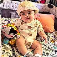 Antonio joined the competition — help win amazing prizes! baby, infant, child, onesie, hat, plush_toy, toy, blanket, pillow, playpen, socks, sitting, smile, chubby_cheeks, cute, indoor, portrait, playmat, gaze, nursery