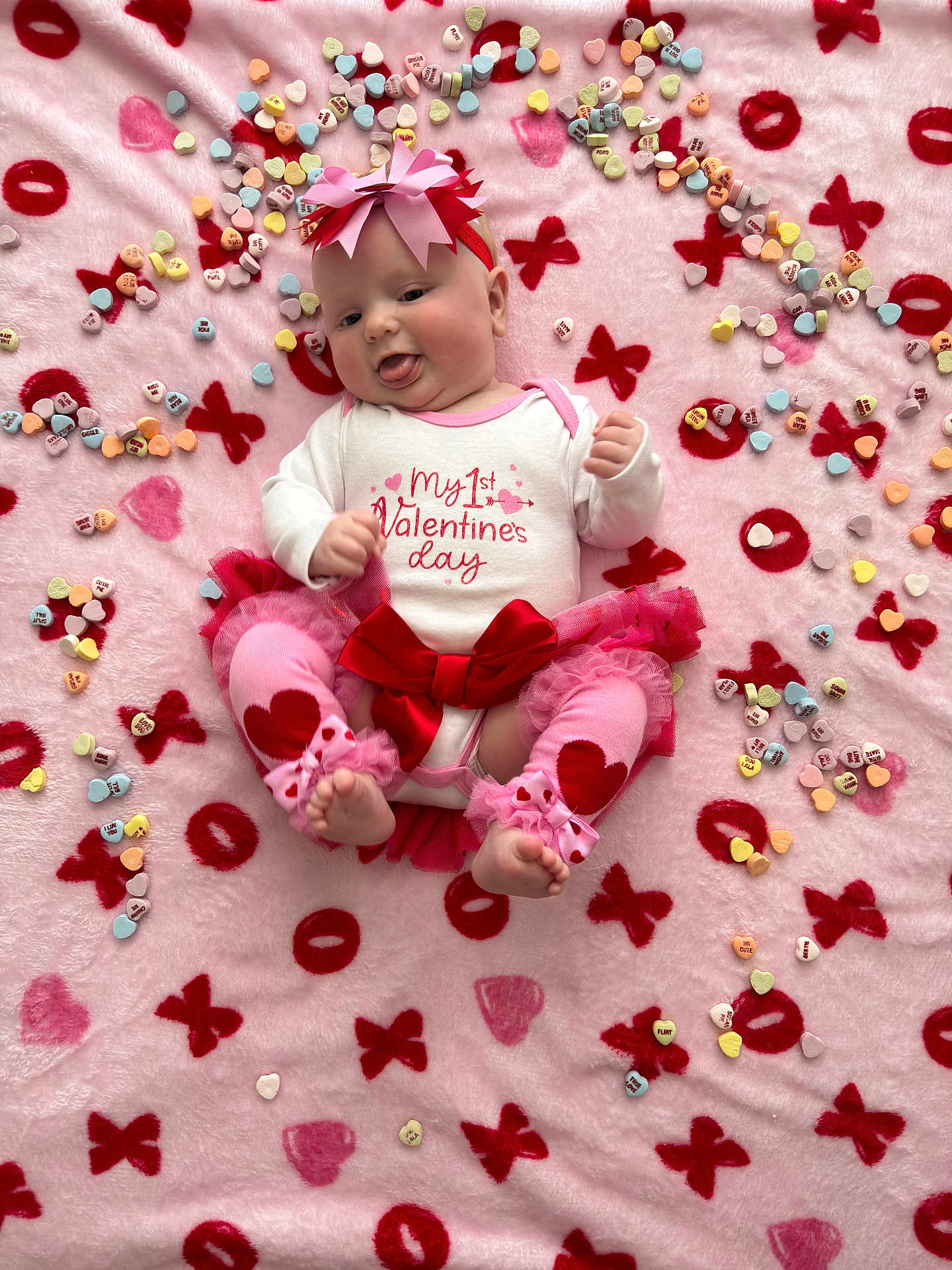 Scarlette joined the competition — help win amazing prizes! baby, infant, pink_blanket, valentines_day, heart_candies, red_bow, headband, tutu, cute, tongue_out, celebration, holiday, xoxo_pattern, leg_warmers, baby_clothes, festive, lying_down, colorful, soft_texture, adorable
