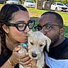 puppy, dog, people, couple, portrait, selfie, outdoor, grass, trees, parked_cars, recycling_bins, sunglasses, eyeglasses, kiss, affection, fluffy, white_dog, long_hair, smiling, sunny
