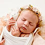 baby, newborn, sleeping, soft_toy, knitted_bunny, flower_headband, wrapped, white_cloth, peaceful, portrait, cute, infant, closeup, soft_background, warm_colors, fingers, toes, cocoon, blanket, adorable