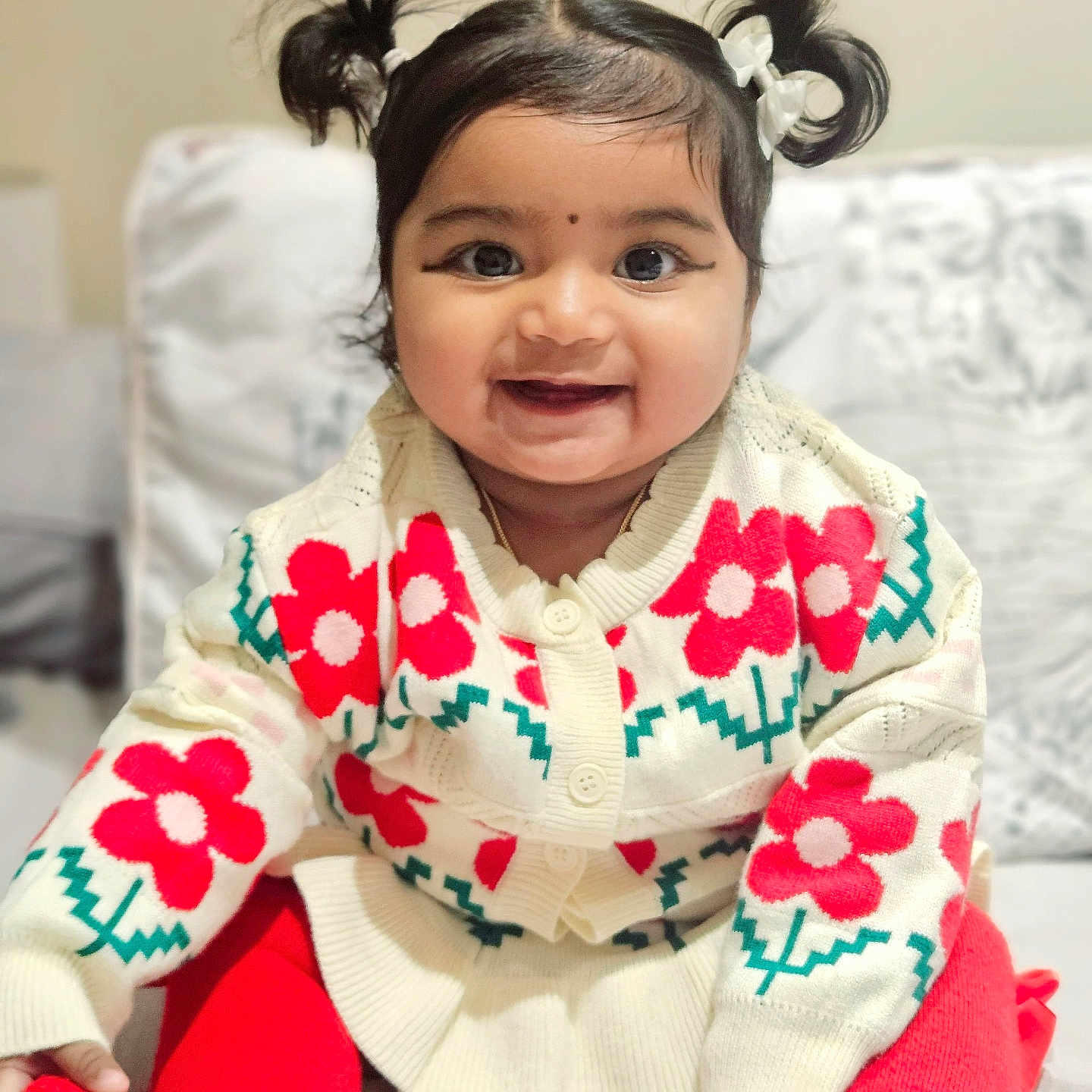 Iza is registered to the contest to win money with this photo: baby, child, couch, cozy, cute, face, happy, home, indoors, infant, person, pigtails, portrait, red_flowers, red_tights, sitting, smiling, sweater, warm_clothing, young_child