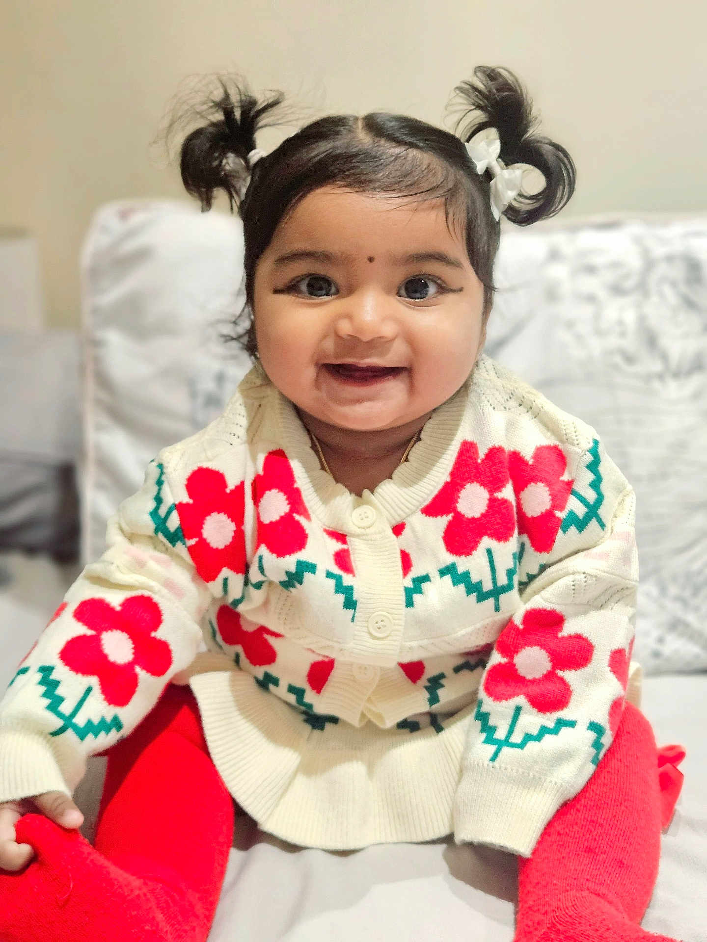 Iza is registered to the contest to win money with this photo: baby, child, smiling, pigtails, sweater, red_flowers, red_tights, sitting, indoors, couch, cozy, cute, portrait, happy, face, person, young_child, warm_clothing, home, infant
