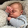 baby, sleeping, blanket, soft, fluffy, onesie, striped_clothing, infant, peaceful, closeup, face, hand, cute, resting, newborn, cozy, portrait, skin, head, relaxation