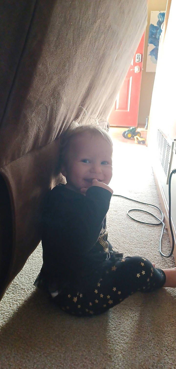 Alanni is registered to the contest to win money with this photo: baby, baby_toddler_clothing, child, curtain, eye, floor, flooring, fun, hardwood, head, human_body, human_leg, joint, knee, leg, person, sitting, smile, tints_and_shades, toddler