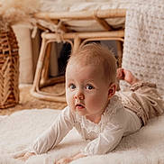 Louisa participe au concours pour gagner de l'argent avec cette photo : baby, infant, blue_eyes, lying_on_stomach, fluffy_rug, woven_mat, wicker_chair, neutral_colors, soft_texture, cozy, indoors, portrait, cute, chubby_cheeks, curious_expression, natural_light, nursery, white_clothing, hands, closeup