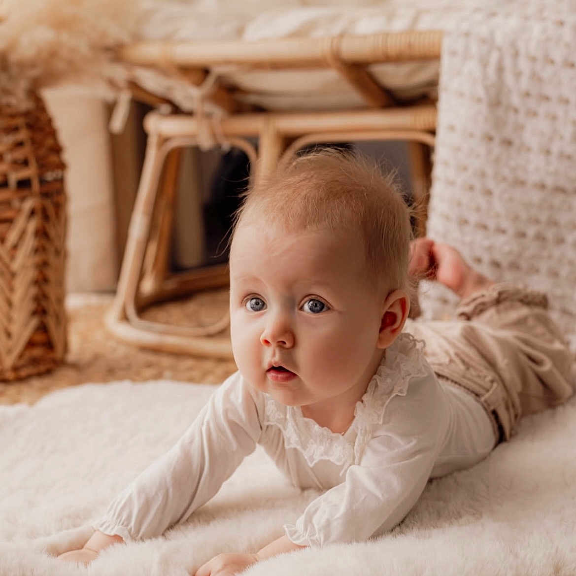 Louisa participe au concours pour gagner de l'argent avec cette photo : baby, blue_eyes, chubby_cheeks, closeup, cozy, curious_expression, cute, fluffy_rug, hands, indoors, infant, lying_on_stomach, natural_light, neutral_colors, nursery, portrait, soft_texture, white_clothing, wicker_chair, woven_mat