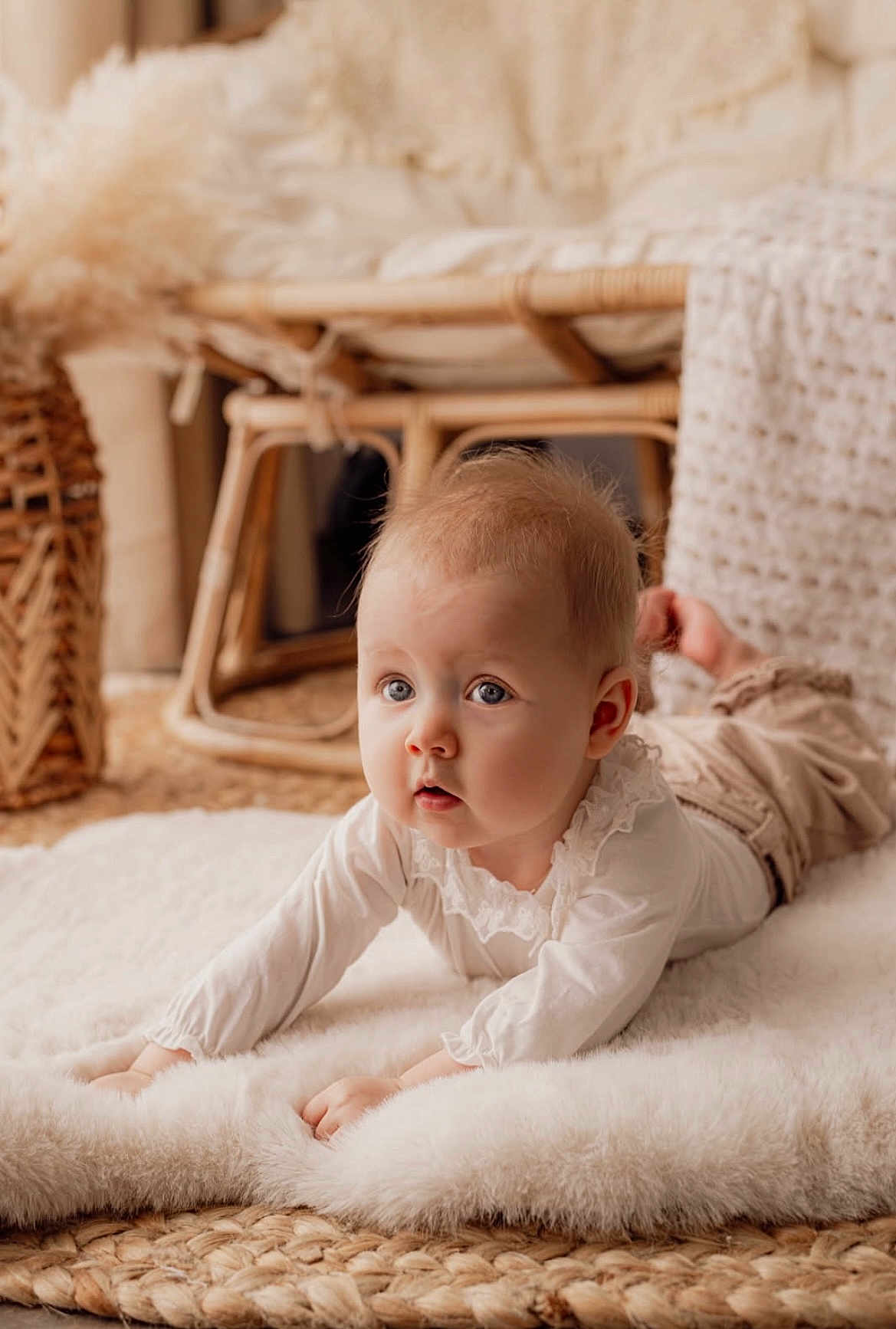 Louisa participe au concours pour gagner de l'argent avec cette photo : baby, infant, blue_eyes, lying_on_stomach, fluffy_rug, woven_mat, wicker_chair, neutral_colors, soft_texture, cozy, indoors, portrait, cute, chubby_cheeks, curious_expression, natural_light, nursery, white_clothing, hands, closeup