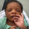 Tru is registered to the contest to win money with this photo: baby, newborn, infant, child, blanket, hand, face, green_clothing, person, plaid, lap, outdoor, concrete, skin, peaceful, resting, portrait, closeup, young, sleepy