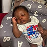 baby, sleeping, infant, pillow, cushion, onesie, clothing, hand, face, peaceful, indoor, closeup, cute, child, resting, dark_skin, curly_hair, soft, comfort, relaxation