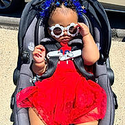 Haven is registered to the contest to win money with this photo: baby, car_seat, sunglasses, red_dress, headband, butterfly, outdoor, sunlight, child, fashion, accessory, cute, infant, seatbelt, summer, person, happy, legs, skin, fun