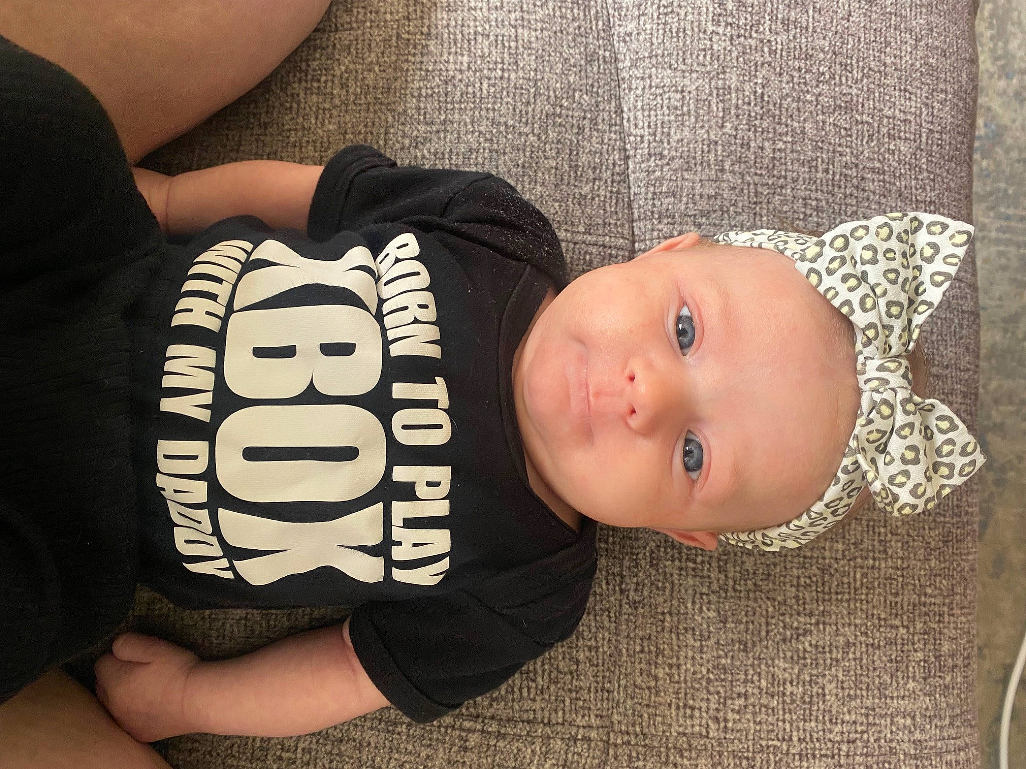 Mariya is registered to the contest to win money with this photo: baby, baby_toddler_clothing, cheek, child, comfort, elbow, face, person, product, sitting, sleeve, smile, t_shirt, toddler, wood, wrist