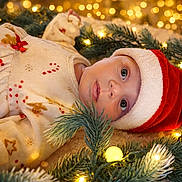 Romi a rejoint le concours — aidez-le/la à gagner de superbes lots ! baby, child, santa_hat, christmas_lights, pine_branches, holiday, festive, pajamas, cute, portrait, face, indoors, celebration, newborn, smiling, christmas, seasonal, soft_lighting, holiday_decor, cozy