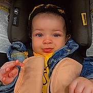 Gianna is registered to the contest to win money with this photo: baby, child, car_seat, denim_jacket, toy, beads, headband, curly_hair, smile, face, hand, straps, safety, infant, cute, portrait, indoor, clothing, closeup, seatbelt