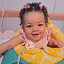 baby, child, smiling, curly_hair, hair_clips, baby_walker, yellow, teal, pacifier_clip, pink_clothing, indoor, cute, happy, infant, playtime, portrait, person, seat, toy, young