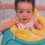 baby, child, curly_hair, hair_clips, blue_eyes, baby_walker, yellow, teal, pacifier_clip, infant, cute, indoor, person, expression, sitting, clothing, pink, playtime, adorable, face