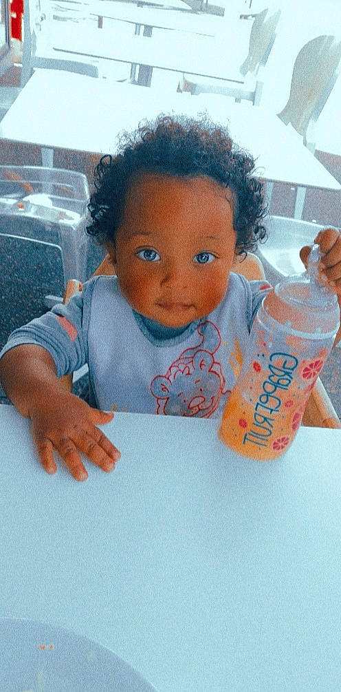 Layanah participe au concours pour gagner de l'argent avec cette photo : bottle, carbonated_soft_drinks, child, drinking_water, drinkware, finger, fun, hand, happy, leisure, liquid, orange_drink, orange_soft_drink, person, plastic_bottle, play, skin, soft_drink, table, toddler