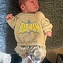 Kayden is registered to the contest to win money with this photo: baby, batman, blurred, carpet, child, clothing, couch, cute, fabric, feet, footwear, hands, indoor, infant, pants, person, relaxed, sleepy, small, sweatshirt